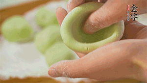 將均分的艾草面團搓成圓，挖一個窩，放入餡心，再搓成圓。