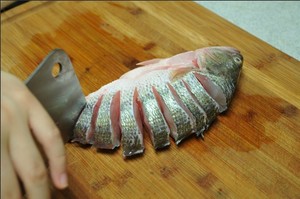 將鱸魚清洗干凈，從脊椎處切斷至腹部，腹部保留1cm左右不要切斷。