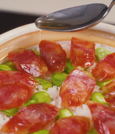 大米出現(xiàn)小孔時(shí)開(kāi)蓋放香腸，往鍋邊淋入少許油，再燜煮8~10分鐘左右。