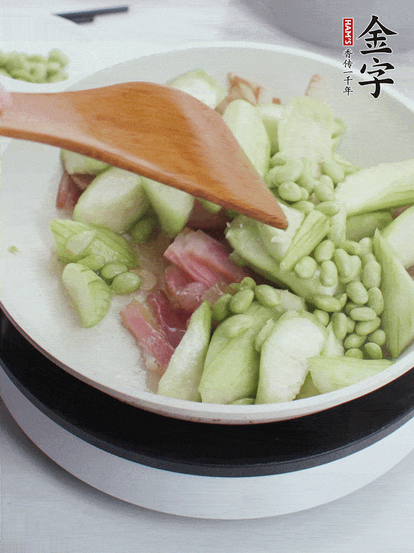 依次下絲瓜、青豆翻炒，炒至絲瓜打蔫縮小。