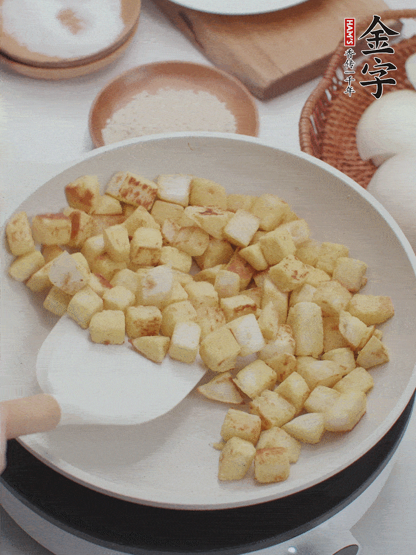 起鍋熱油，倒入饅頭丁，小火煎至蛋液凝固定型再翻面，饅頭丁部煎至金黃時(shí)盛起待用。