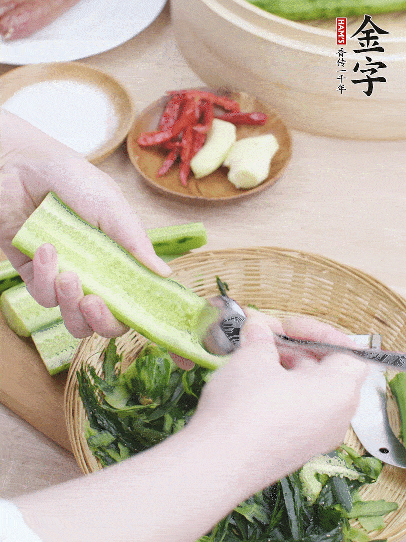 黃瓜削皮，對半切開，勺子挖去內(nèi)瓤，斜刀切片。青蒜斜刀切段。